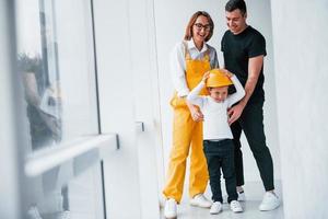 trabalhadora de uniforme amarelo em pé dentro de casa com homem e criança foto