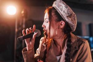 jovem bela cantora ensaiando em um estúdio de gravação foto