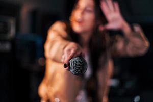 close-up vista do microfone. jovem bela artista feminina ensaiando em um estúdio de gravação foto
