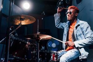 toca bateria. jovem artista afro-americana ensaiando em um estúdio de gravação foto