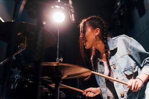 toca bateria. jovem bela artista feminina ensaiando em um estúdio de gravação foto