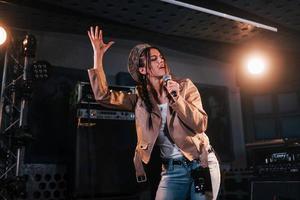 jovem bela cantora ensaiando em um estúdio de gravação foto