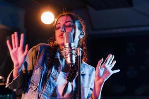 jovem bela artista feminina canta e ensaia em um estúdio de gravação foto