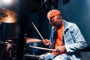 toca bateria. jovem artista afro-americana ensaiando em um estúdio de gravação foto