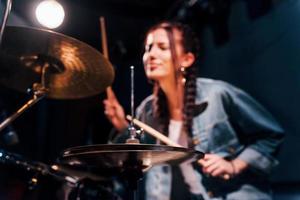 toca bateria. jovem bela artista feminina ensaiando em um estúdio de gravação foto