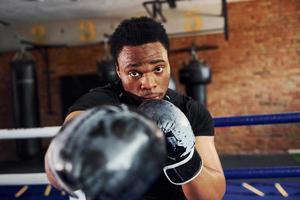 forte boxeador afro-americano em roupas esportivas tem prática na academia foto