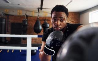 forte boxeador afro-americano em roupas esportivas tem prática na academia foto