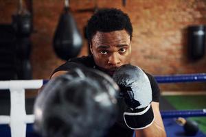 forte boxeador afro-americano em roupas esportivas tem prática na academia foto