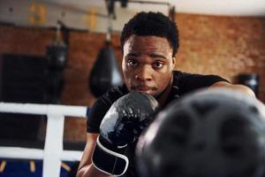 forte boxeador afro-americano em roupas esportivas tem prática na academia foto