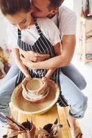 com o namorado ou marido. jovem ceramista feminina trabalha em ambientes fechados com produtos de argila feitos à mão. concepção de cerâmica foto