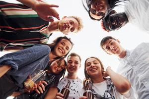 olhando para baixo. vista de baixo. grupo de jovens em roupas casuais faz uma festa no telhado juntos durante o dia foto