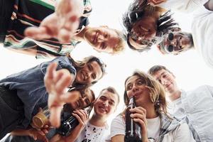 olhando para baixo. vista de baixo. grupo de jovens em roupas casuais faz uma festa no telhado juntos durante o dia foto