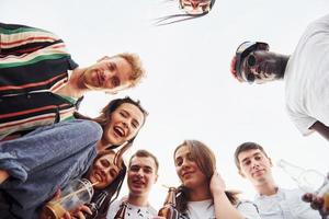 olhando para baixo. vista de baixo. grupo de jovens em roupas casuais faz uma festa no telhado juntos durante o dia foto