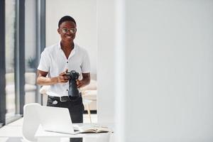 câmera de teste. jovem afro-americano em roupas formais está no escritório foto