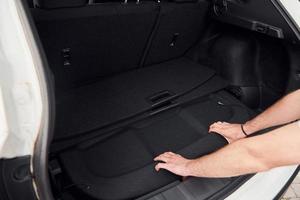mãos de mulher abrindo o porta-malas do carro. vista de perto. automóvel moderno branco foto