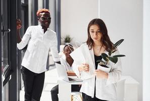 menina europeia triste vai embora. grupo de empresários afro-americanos trabalhando juntos no escritório foto