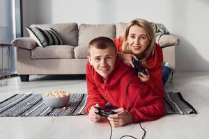 jovem casal adorável juntos em casa jogando videogame no fim de semana e feriados juntos foto