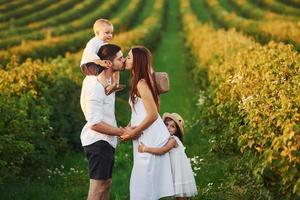 família de quatro pessoas passando o tempo livre no campo no dia ensolarado do verão foto