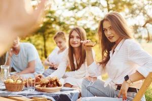 mulher dando mais cinco ao fotógrafo. grupo de jovens tem férias ao ar livre na floresta. concepção de fim de semana e amizade foto