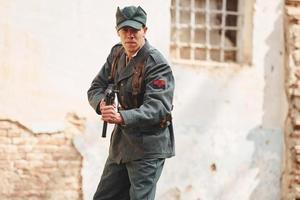 ternopil, ucrânia - junho de 2020, filmagem do filme do exército insurgente ucraniano. fotos dos bastidores. jovem soldado com arma perto de prédio antigo