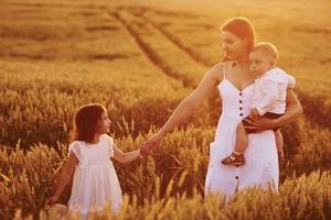 alegre família de mãe, filho e filha passar o tempo livre no campo em dia ensolarado de verão foto