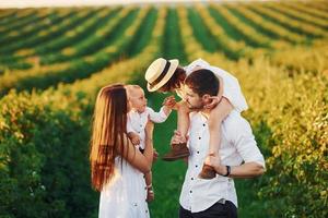 no campo agrícola. pai, mãe com filha e filho passando o tempo livre ao ar livre no dia ensolarado do verão foto