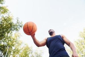 Tempo nublado. homem afro-americano joga basquete na quadra ao ar livre foto