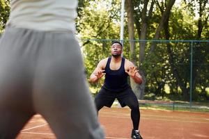 homem afro-americano com garota joga basquete na quadra ao ar livre foto