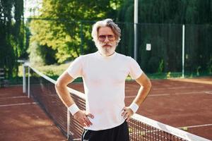 concepção de moda. em óculos de sol. homem estiloso moderno sênior ao ar livre no campo esportivo durante o dia foto