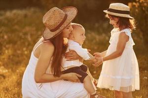 família feliz de mãe, filho e filha passar o tempo livre no campo em dia ensolarado de verão foto