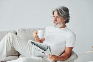 ter tempo livre. homem moderno elegante sênior com cabelos grisalhos e barba dentro de casa foto