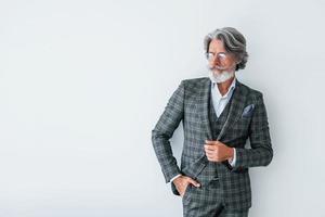 posando para a câmera. homem moderno elegante sênior com cabelos grisalhos e barba dentro de casa foto