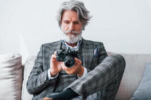 em apartamento com roupas elegantes. homem moderno elegante sênior com cabelos grisalhos e barba dentro de casa foto