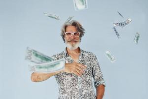 milionário com dinheiro nas mãos. homem moderno elegante sênior com cabelos grisalhos e barba dentro de casa foto