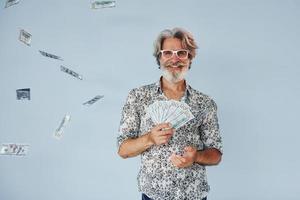 milionário com dinheiro nas mãos. homem moderno elegante sênior com cabelos grisalhos e barba dentro de casa foto