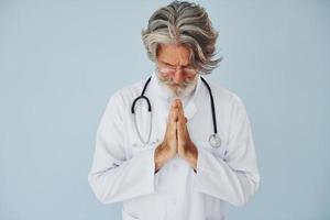 profissional médico positivo. homem moderno elegante sênior com cabelos grisalhos e barba dentro de casa foto