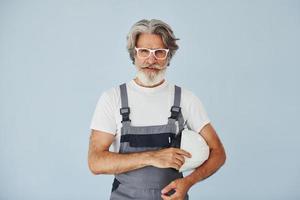 reparador pronto para o trabalho. homem moderno elegante sênior com cabelos grisalhos e barba dentro de casa foto