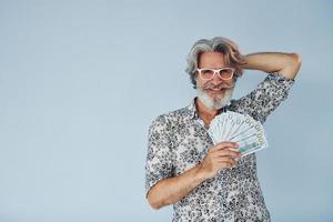 milionário com dinheiro nas mãos. homem moderno elegante sênior com cabelos grisalhos e barba dentro de casa foto