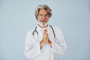 profissional médico positivo. homem moderno elegante sênior com cabelos grisalhos e barba dentro de casa foto