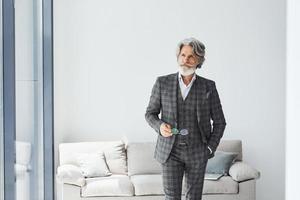 concepção de estilo bonito. homem moderno elegante sênior com cabelos grisalhos e barba dentro de casa foto