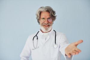 profissional médico positivo. homem moderno elegante sênior com cabelos grisalhos e barba dentro de casa foto