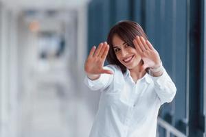 morena de camisa branca posando dentro de casa no aeroporto moderno ou corredor durante o dia foto