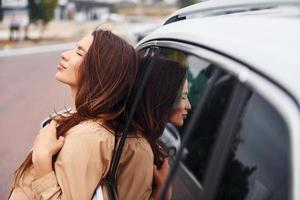 encosta na porta. mulher jovem e bonita na moda e seu automóvel moderno foto