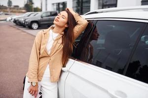 encosta na porta. mulher jovem e bonita na moda e seu automóvel moderno foto