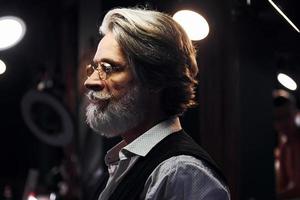 elegante homem sênior moderno com cabelos grisalhos e barba está dentro de casa foto