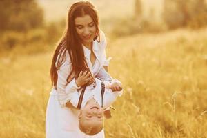 jovem mãe com seu filho pequeno está ao ar livre no campo agrícola. lindo sol foto