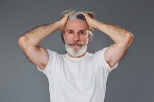 belo retrato. elegante homem sênior moderno com cabelos grisalhos e barba está dentro de casa foto