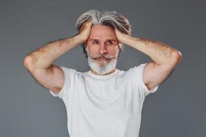 belo retrato. elegante homem sênior moderno com cabelos grisalhos e barba está dentro de casa foto