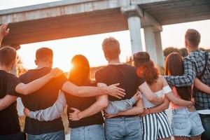 vista de trás. grupo de jovens amigos alegres se divertindo juntos. festa ao ar livre foto