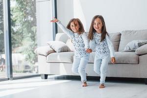 duas meninas bonitinhas dentro de casa juntas. crianças se divertindo foto